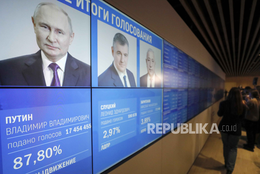 Orang-orang berdiri di depan layar dengan hasil awal pemilihan presiden di Komisi Pemilihan Umum Pusat di Moskow, Rusia, (17/3/2024).