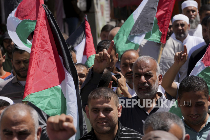  Warga Palestina mengibarkan bendera nasional mereka sambil mengangkat tangan dan meneriakkan slogan-slogan selama rapat umum solidaritas dengan Al-Quds, atau Yerusalem, di jalan utama di Khan Younis, Jalur Gaza selatan, Jumat, 9 September 2022.