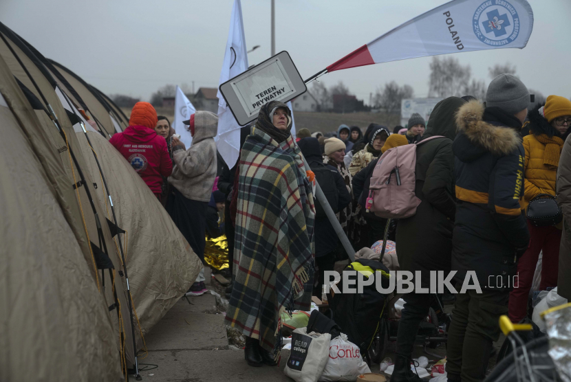 Seorang wanita menghangatkan dirinya dengan selimut di tengah kerumunan pengungsi setelah melarikan diri dari Ukraina dan tiba di perbatasan di Medyka, Polandia, Senin, 7 Maret 2022. 