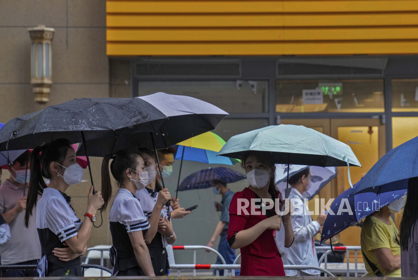 Pekerja dan warga yang mengenakan masker berbaris di tengah hujan untuk tes COVID-19 di luar lingkungan di Beijing, Rabu, 22 Juni 2022. Laporan surat kabar pro Pemerintah China Global Times menyatakan, populasi China telah melambat secara signifikan dan diperkirakan akan mulai menyusut menjelang 2025.
