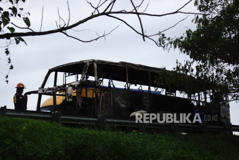 Petugas berdiri di dekat Bus Pahala Kencana yang ludes terbakar di ruas tol Jombang-Mojokerto (Jomo) KM 705 A Desa Blimbing, Kecamatan Kesamben, Kabupaten Jombang, Jawa Timur, Rabu (17/4/2024). 