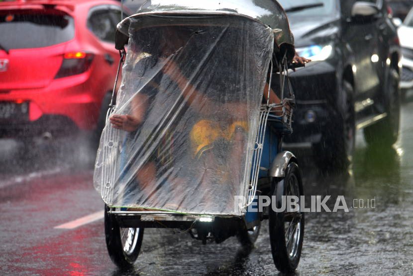 Wisatawan menggunakan becak motor saat hujan di kawasan Ngabean, Yogyakarta.