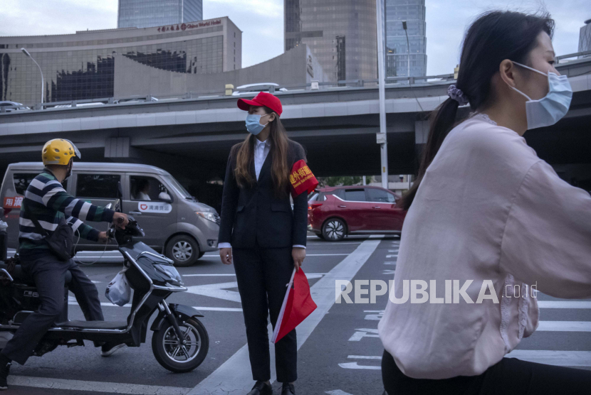  Seorang penjaga penyeberangan yang mengenakan masker untuk melindungi diri dari Covid-19 berdiri di persimpangan di kawasan pusat bisnis di Beijing, Kamis, 16 September 2021. Beijing dibayangi gelombang baru Covid-19 varian Delta setelah ditemukan empat kasus baru.