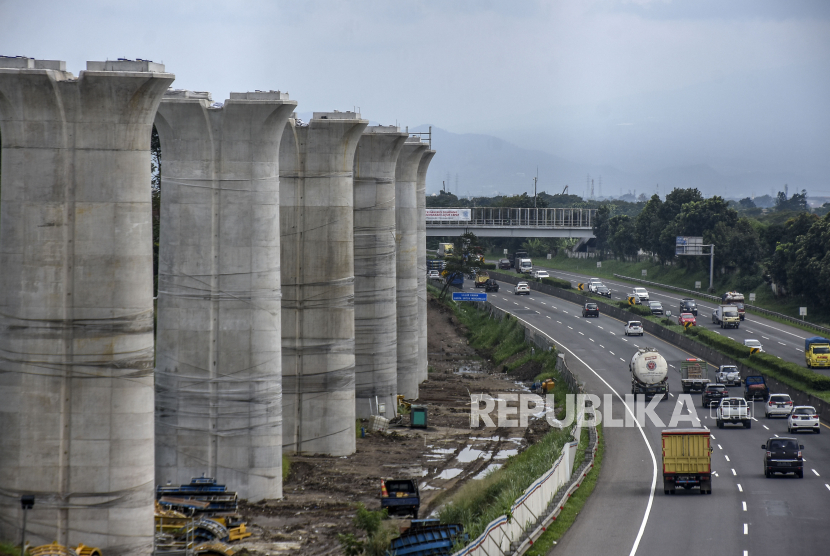 Kendaraan melintas di dekat kontruksi tiang pancang untuk jalur kereta pada proyek Kereta Cepat Jakarta-Bandung di kawasan Jalan Tol Padaleunyi, Kota Cimahi.