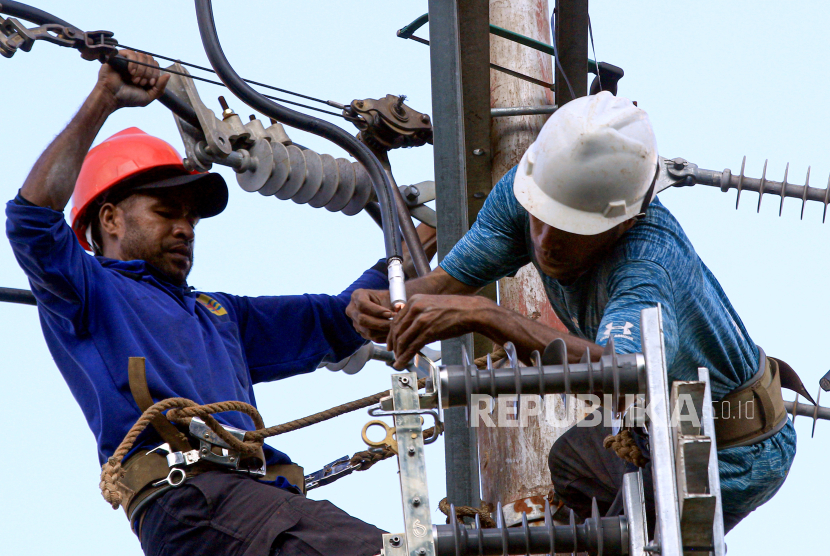 Dua pekerja memasang perangkat jaringan listrik di jalan Manda, Distrik Jayapura Utara, Kota Jayapura, Papua, Selasa (5/8/2023). 