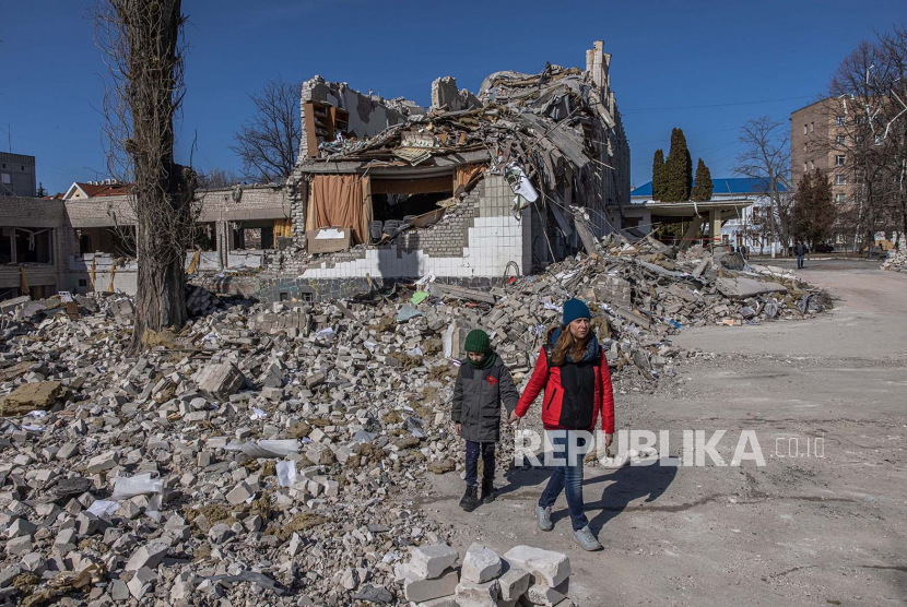 Wanita dengan anak laki-laki mengunjungi area sekolah yang rusak parah setelah penembakan Rusia, di kota Zhytomyr, barat laut Ukraina, 20 Maret 2022. 