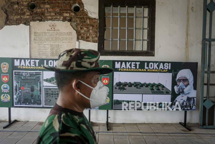 Anggota TNI melintas di depan gambar maket lokasi pembangunan Rumah Sakit Lapangan khusus Covid 19. (ilustrrasi)