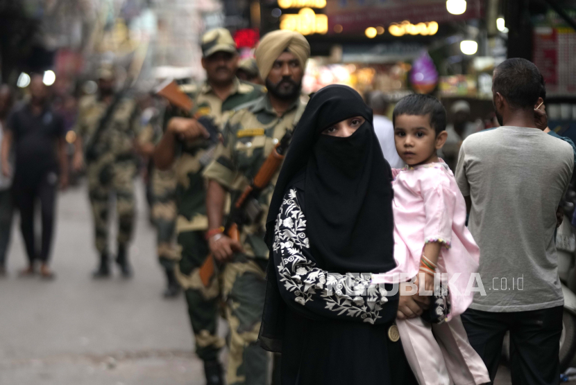 Seorang wanita Muslim bersama anaknya berjalan melewati patroli pasukan paramiliter di kawasan tua Delhi, India, Sabtu, 9 September 2023.