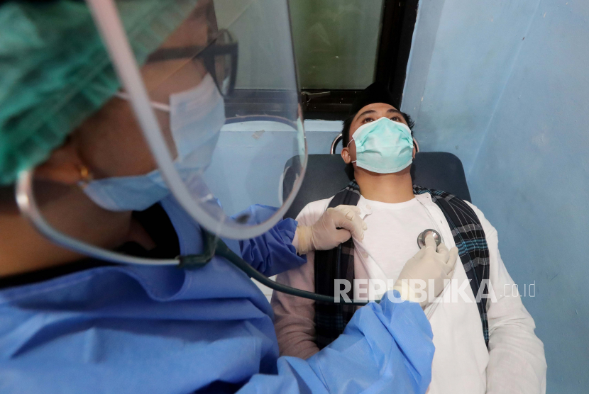 Guru Besar Unpad Bantah Isu Vaksin Covid-19 tidak Aman. Seorang petugas Indonesia yang mengenakan alat pelindung memeriksa jantung dan pernapasan pengunjung selama simulasi imunisasi COVID-19 di Depok, Jawa Barat, Indonesia, 22 Oktober 2020. Setidaknya 2.200 orang relawan di seluruh negeri akan menerima vaksin penyakit COVID-19 di akhir tahun 2020. Pemerintah Indonesia akan memantau kesehatan fisik secara rutin dan jika uji coba terbukti berhasil, pemerintah akan memproduksi 250 juta dosis vaksin pada tahun 2021. 