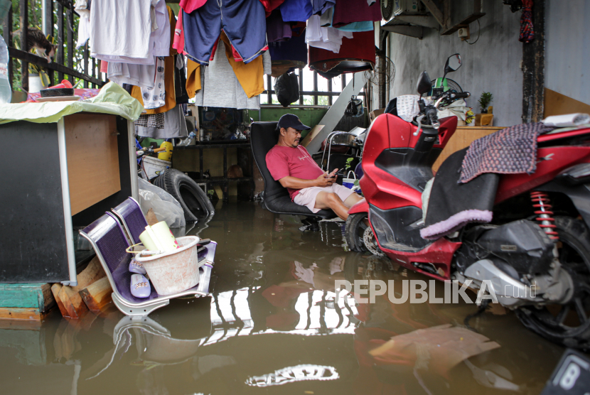 Seorang warga duduk di halaman rumahnya yang terendam banjir di kawasan Benda, Kota Tangerang, Banten.