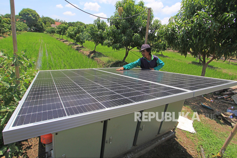 Petani membersihkan permukaan panel surya (solar cell) di area lahan tumpang sari miliknya di Kelurahan Karanganyar, Indramayu, Jawa Barat, Kamis (12/11/2020). 