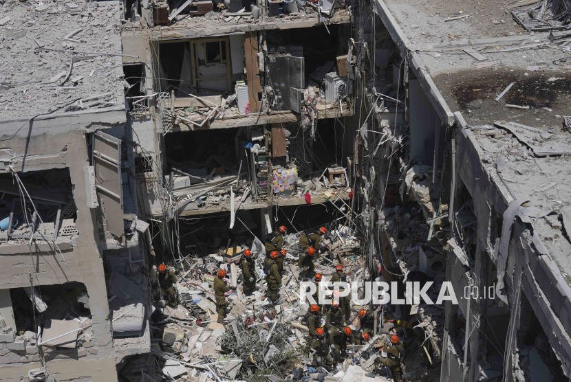Tentara Israel mencari korban selamat di tengah reruntuhan bangunan tempat tinggal yang hancur akibat serangan rudal Iran di kota Bat Yam, Israel tengah, Ahad (15/6/2025).