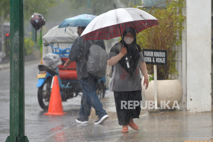 Warga menggunakan payung menembus hujan di kawasan Tugu Pal Putih, Yogyakarta, Senin (17/10/2022). BPBD Yogyakarta Siaga 24 Jam Antisipasi Cuaca Ekstrem 