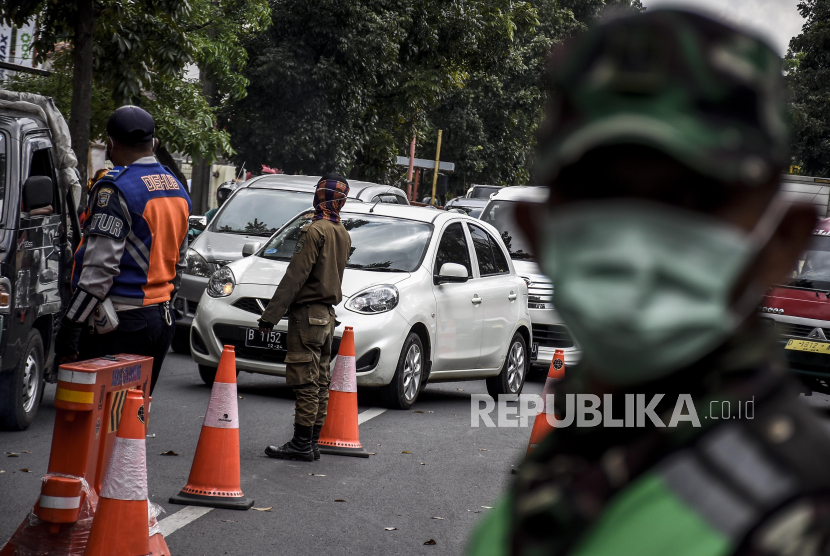 Petugas gabungan mengatur arus lalu lintas di pos pemeriksaan Pembatasan Sosial Berskala Besar (PSBB). Ilustrasi