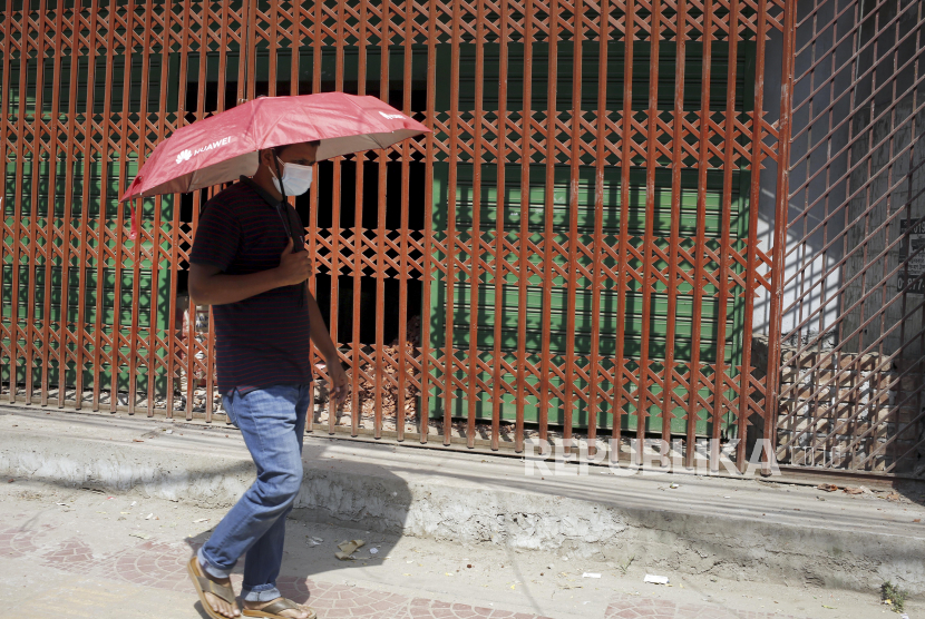 Seorang warga menggunakan payung untuk melindungi diri dari gelombang panas. ilustrasi