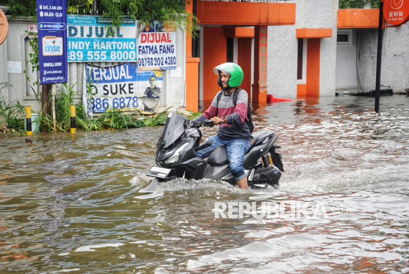 Pengendara kendaraan bermotor melintasi banjir rob di Kawasan Pluit Karang Ayu Barat, Jakarta, Senin (16/12/2024).