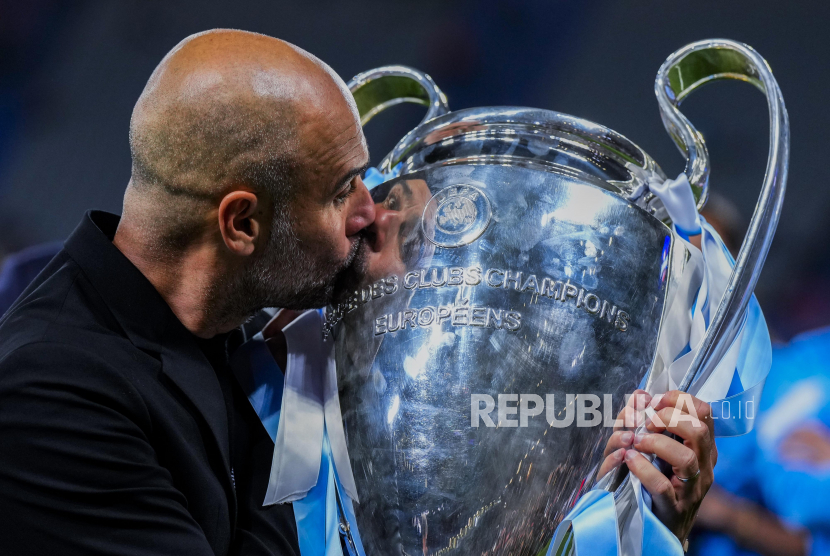 Pep Guardiolan mencium trofi juara Liga Champions.