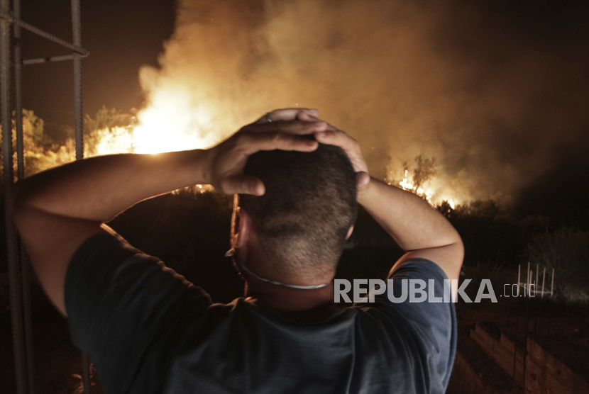 Seorang pria melihat kebakaran hutan di dekat desa Larbaa Nath Irathen, rapi Tizi Ouzou, di wilayah pegunungan Kabyle, 100 kilometer (60 mil) timur ibu kota Aljazair, Aljir, Rabu, 11 Agustus 2021. 
