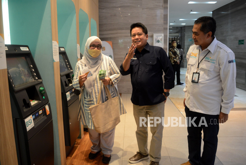 Direktur Utama BSI Hery Gunardi (tengah) didampingi RCEO BSI Jakarta 1 Deden Durachman (kanan) berbincang dengan nasabah yang telah selesai menarik uang tunai dari mesin anjungan tunai mandiri (ATM) di Kantor Cabang Jakarta Thamrin, Jakarta, Kamis (11/5/2023). Layanan perbankan PT Bank Syariah Indonesia Tbk (BSI) telah kembali normal, baik di kantor cabang, mesin anjungan tunai mandiri (ATM) maupun mobile banking sehingga dapat digunakan oleh nasabah untuk bertransaksi. 