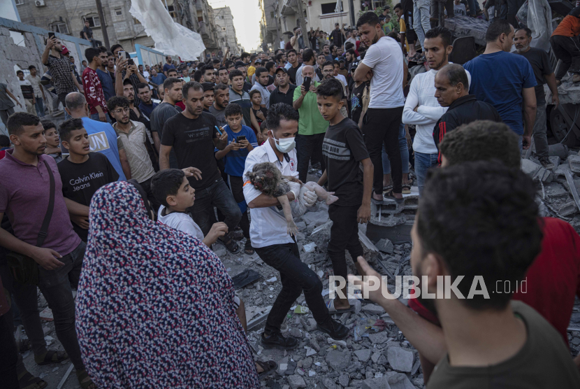 Petugas medis mengevakuasi jenazah seorang anak dari reruntuhan bangunan di Jalur Gaza. 