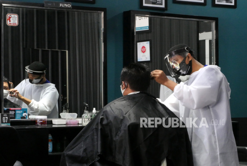 Kapster menggunakan masker dan pelindung wajah saat mencukur rambut pengunjung di Arfa Barbershop, Yogyakarta, Senin (8/6). Risiko penyebaran dan penularan Covid-19 di barber shop dan salon bisa ditekan dengan menjalankan protokol kesehatan.