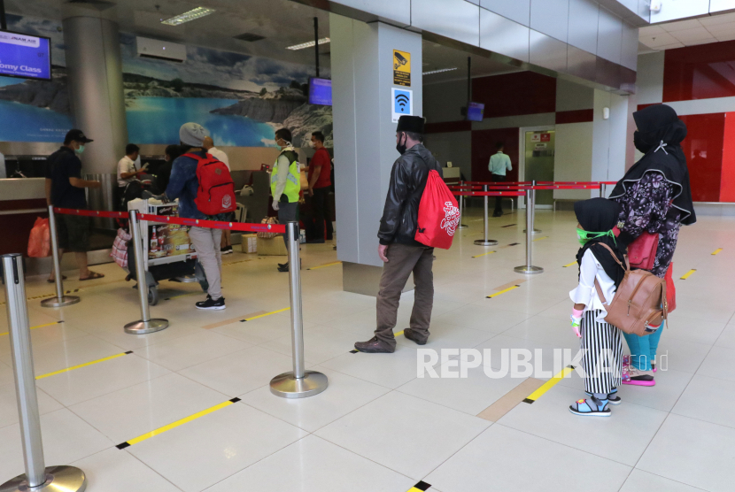 Penumpang mengantre di lantai yang telah diberi stiker panduan jarak di Bandara Depati Amir, Kota Pangkalpinang, Kepulauan Bangka Belitung, Kamis (19/3/2020). 