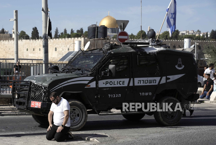 Sebuah kendaraan lapis baja zionis Israel melewati seorang jamaah Muslim Palestina yang dilarang memasuki Masjid Al-Aqsa salat di luar Kota Tua Yerusalem, Jumat (10/11/2023).