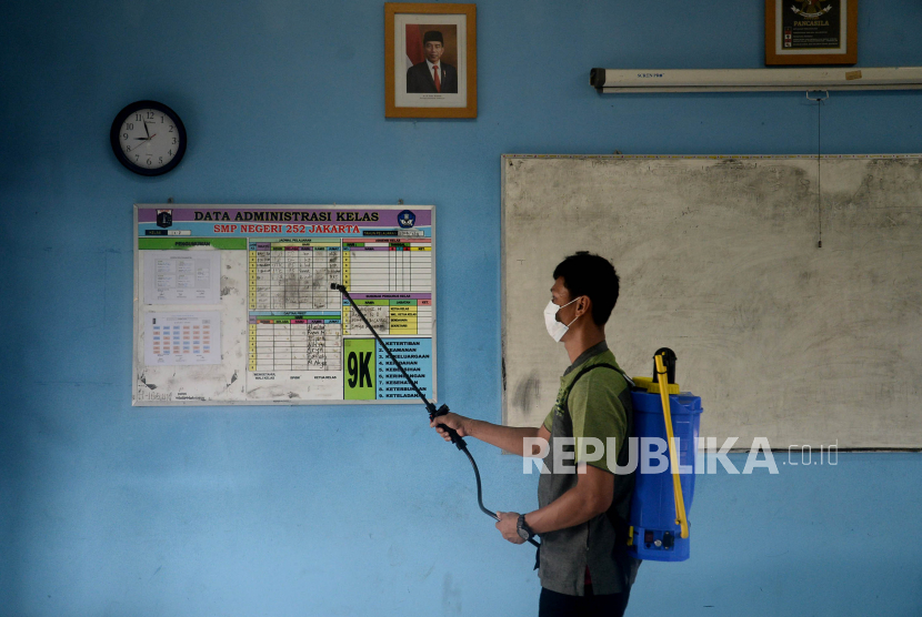 Petugas menyemprotkan disinfektan di SMPN 252 Duren Sawit, Jakarta Timur, Jumat (14/1), yang sedang mengehentikan sementara kegiatan PTM 100 persen setelah terdapat satu siswa yang positif Covid-19.