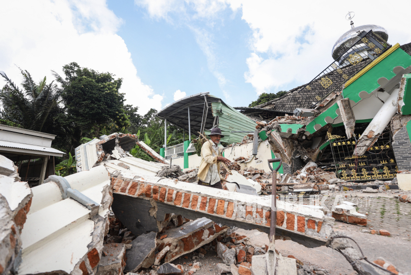 Warga melintas di dekat Masjid Jamik Al Muhajirin yang sebangian bangunannya roboh akibat gempa di Dusun Balikbakgunung, Desa Sangkapura, Pulau Bawean, Kabupaten Gresik, Jawa Timur, Ahad (24/3/2024). 