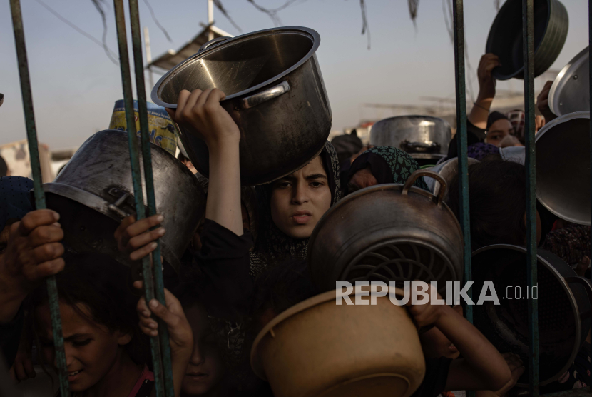 Anak-anak pengungsi di Gaza mengumpulkan makanan di Khan Yunis, Jalur Gaza selatan, 15 Juni 2024. Peran UNRWA sangat vital bagi pengungsi Palestina.