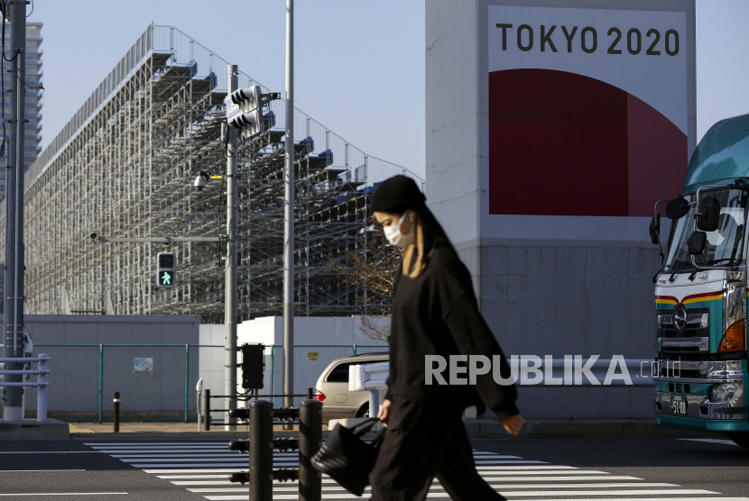  Seorang wanita yang mengenakan masker pelindung melewati bangku untuk kursus BMX Olimpiade Tokyo 2020 Senin, 7 Desember 2020, di Tokyo.