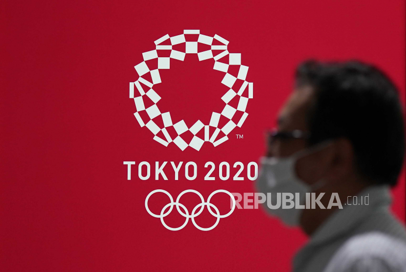 Pejalan kaki yang mengenakan masker pelindung sedang berjalan melewati poster acara Olimpiade Tokyo 2020 di Jepang