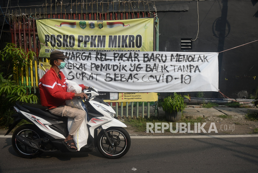 Pengendara melintas di dekat spanduk peringatan untuk pemudik di kawasan Pasar Baru, Jakarta. Pemerintah meminta masyarakat tidak lengah dan terlena dengan fenomena lonjakan kasus Covid-19 pascalebaran 2021 yang tidak separah tahun 2020.