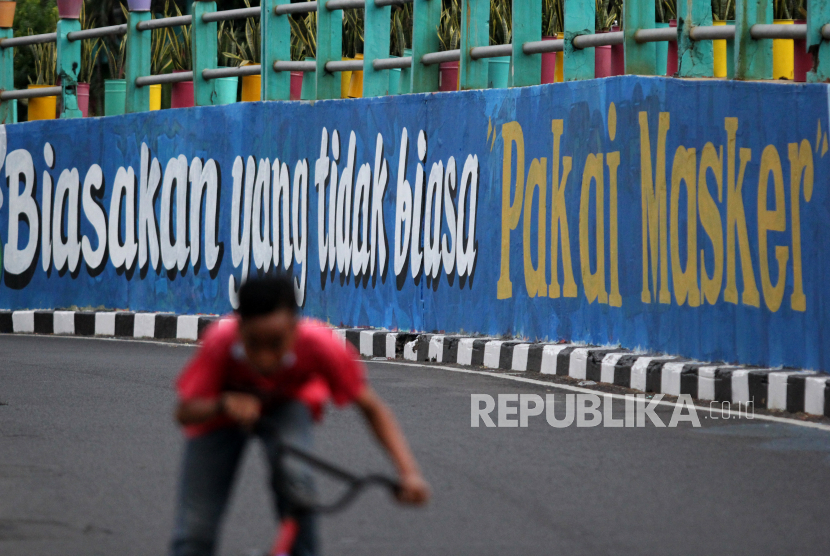 Pesepeda melintas di dekat dinding bermural di Surabaya, Jawa Timur, Ahad (18/10/2020). Mural di sepanjang dinding viaduk Gubeng itu sebagai sarana imbauan kepada masyarakat untuk menerapkan protokol kesehatan pencegahan penularan COVID-19. 