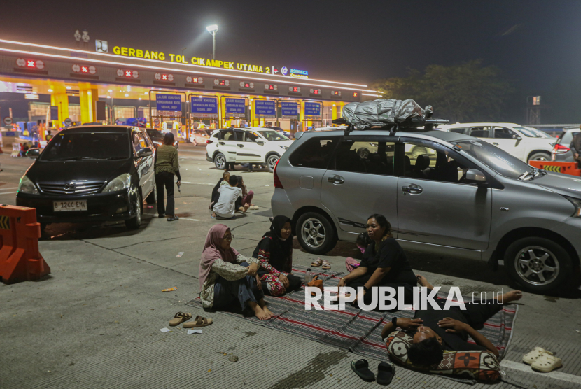 Warga menyantap hidangan saat waktu sahur di Gerbang Tol Cikampek Utama, Karawang, Jawa Barat, Kamis (18/3/2026). Sejumlah pemudik memilih menghabiskan waktu sahur dan beristirahat di bahu jalan Gerbang Tol Cikampek Utama lantaran terjadi penumpukan pemudik di rest area.