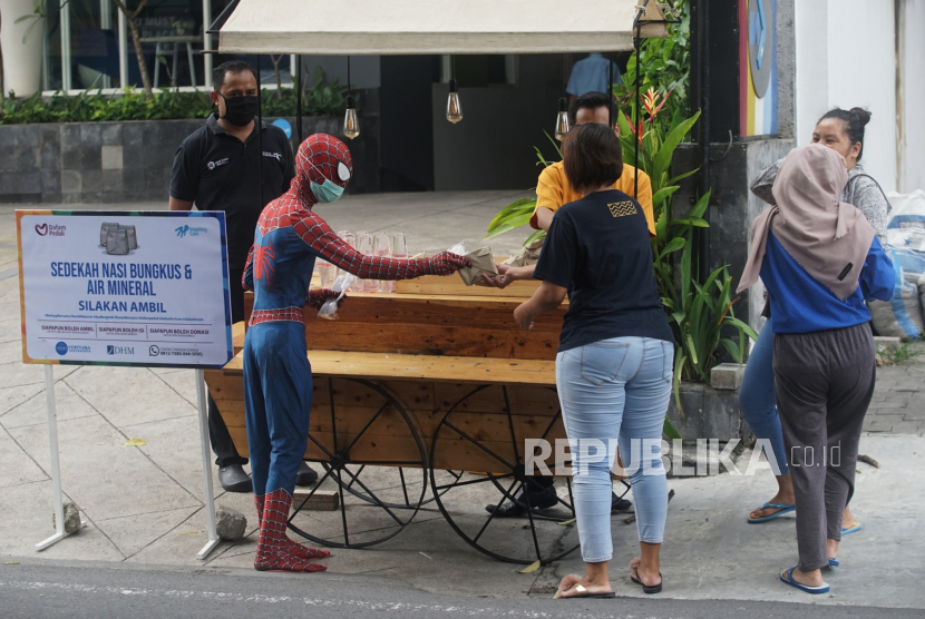 Petugas mengenakan kostum Spiderman membagikan nasi bungkus di depan Hotel Dafam, Seturan, Sleman, D.I Yogyakarta, Rabu (15/4/2020)