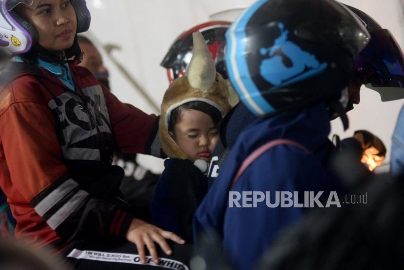 Pemudik sepeda motor yang membawa anaknya mengantri memasuki kapal di Pelabuhan Merak ,Banten, Selasa (12/6) dini hari.