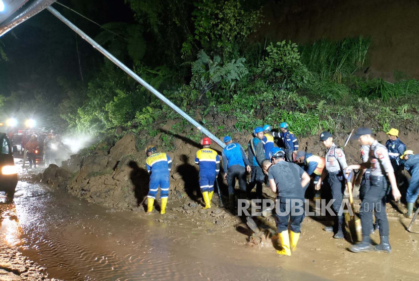 Petugas berupaya membersihkan material tanah longsor yang menutup Jalan Garut-Tasikmalaya di Desa Tenjowaringin, Kecamatan Salawu, Kabupaten Tasikmalaya, Kamis (11/1/2024). 