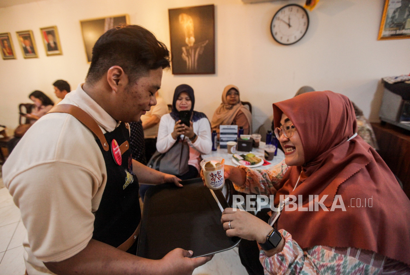 Penyandang down syndrome menyajikan kopi untuk tamu di Kopi Kamu, Kebayoran Baru, Jakarta Selatan, Ahad (3/12/2023). 