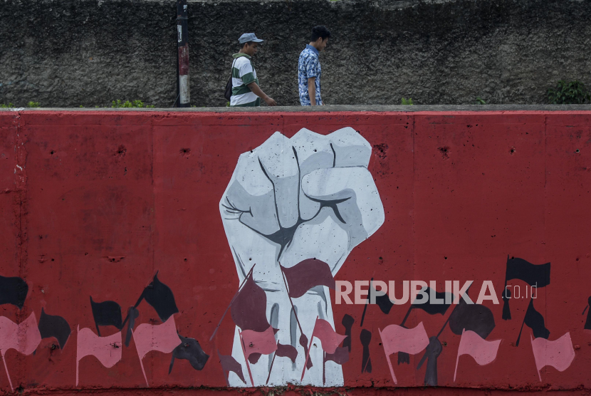 Warga melintas di dekat mural bergambar kepalan tangan dan kibaran bendera di kawasan Kampung Melayu, Jakarta, Kamis (6/8). Ilustrasi
