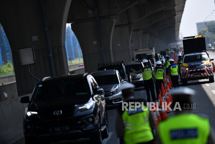 Petugas kepolisian memeriksa sejumlah kendaraan yang melintas. Peraturan Gubernur (Pergub) nomor 47 tahun 2020 mengatur pembatasan kegiatan berpergian keluar dan atau masuk provinsi DKI.