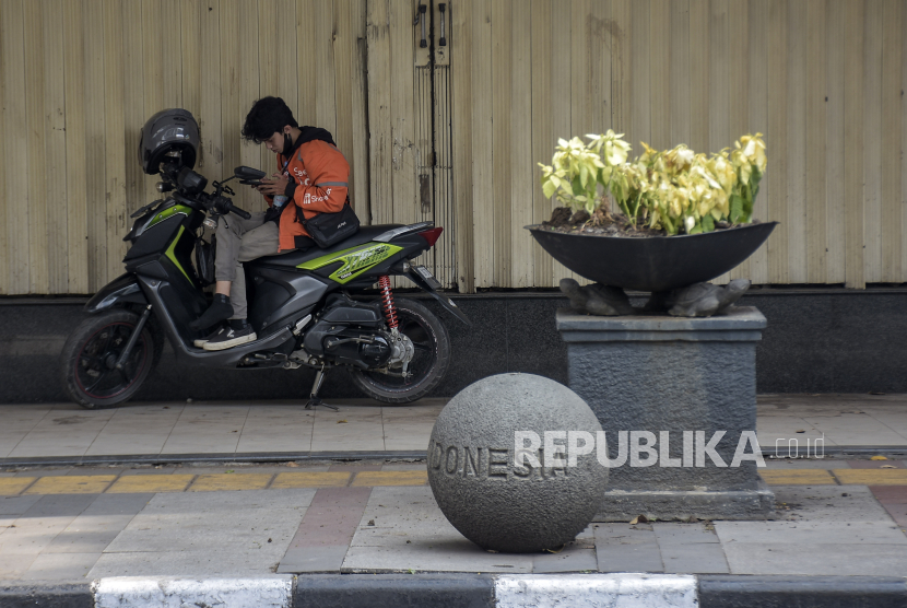 Pengemudi ojek daring berteduh di pedestrian Jalan Asia Afrika, Kota Bandung, Jawa Barat, Rabu (18/10/2023). 