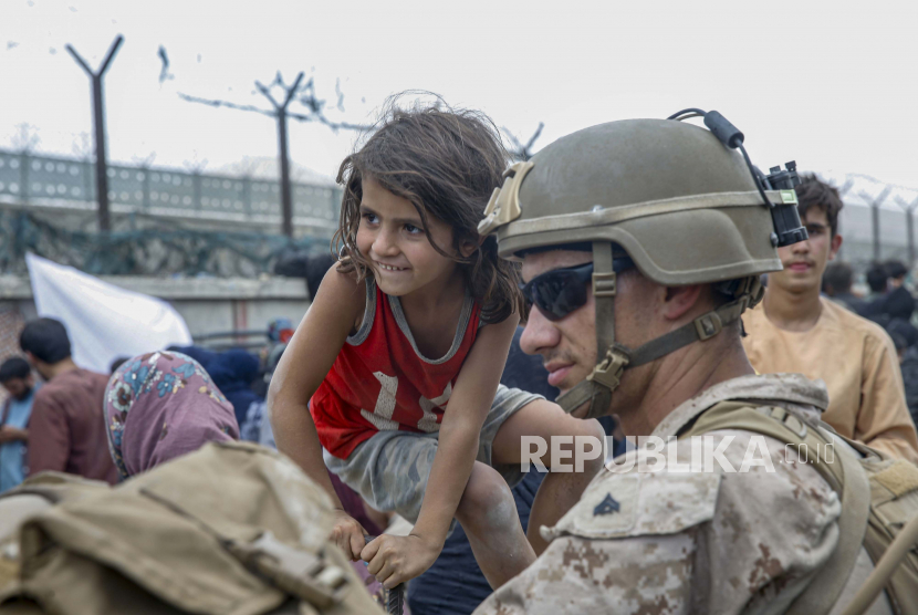  Dalam gambar yang diberikan oleh Marinir AS, seorang Marinir dengan Satuan Tugas Udara-darat Marinir Tujuan Khusus - Tanggap Krisis - Komando Pusat, menunggu dengan seorang anak selama evakuasi di Bandara Internasional Hamid Karzai di Kabul, Afghanistan, Jumat, 20 Agustus, 2021.