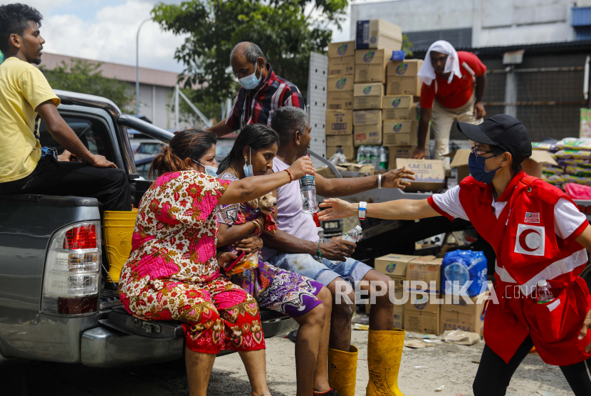 Seorang relawan palang merah (kanan) memberikan minuman kepada para korban setelah banjir melanda Taman Sri Muda, distrik Shah Alam, sekitar 40 km dari Kuala Lumpur, Malaysia, 21 Desember 2021. 