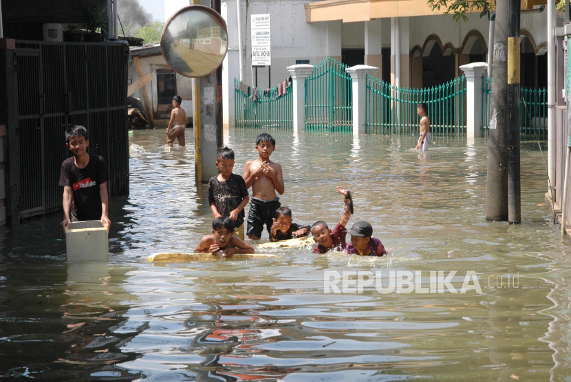 Sejumlah anak bermain di jalan yang terendam banjir di daerah Bojongsoang, Kabupaten Bandung, Ahad (7/5/2023). Banjir akibat luapan air Sungai Citarum yang dipicu curah hujan yang tinggi, kembali merendam sejumlah wilayah di Kecamatan Bojongsoang, Dayeuhkolot, dan Baleendah. Saat ini banjir berangsur-angsur surut, namun dengan intensitas hujan yang masih tinggi, warga dan petugas terkait tetap waspada jika ketinggian air citarum kembali meningkat.