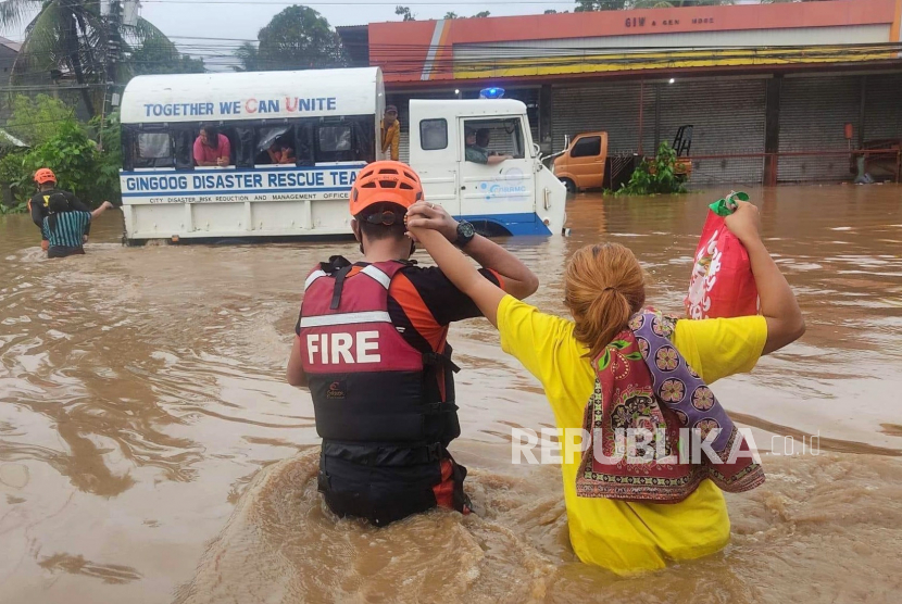 Foto selebaran yang disediakan oleh Biro Perlindungan Kebakaran (BFP) menunjukkan petugas penyelamat menahan seorang penduduk di jalan yang banjir pada hari Natal di kota Gingoog, provinsi Misamis Oriental, Filipina, 25 Desember 2022 (diterbitkan pada 26 Desember 2022). Hujan deras yang disebabkan oleh kejadian cuaca yang disebut 