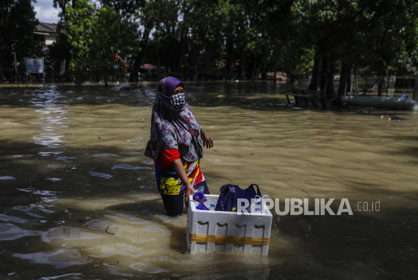 Seorang wanita mendorong gerobaknya ke dalam banjir setelah banjir melanda Taman Sri Muda, distrik Shah Alam, sekitar 40 km dari Kuala Lumpur, Malaysia, 21 Desember 2021. 