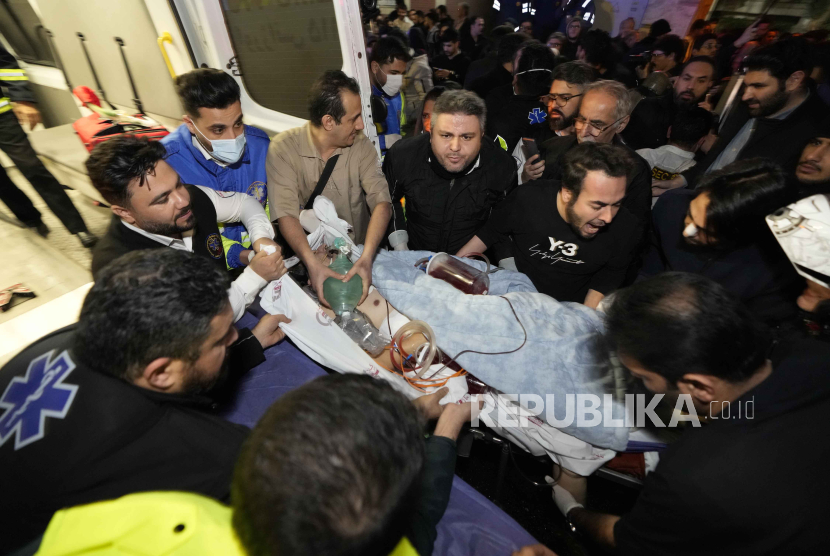 Petugas medis mengevakuasi seorang pasien setelah kebakaran besar terjadi di beberapa lantai rumah sakit Gandhi, di Teheran utara, Iran, Kamis, (25/1/2024).
