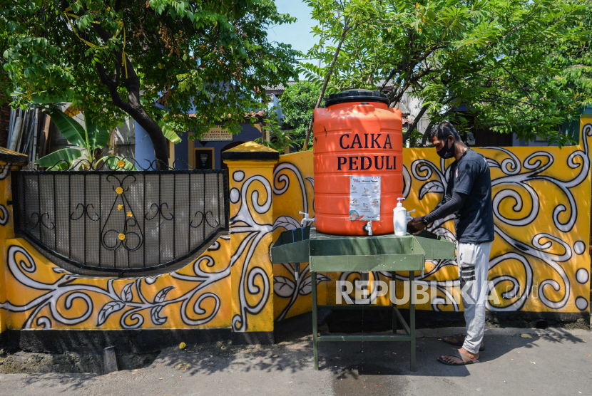 Warga mencuci tangan di kampung Siaga COVID-19 di Kampung Rawa Pasung RW22, Kota Baru, Kota Bekasi, Jawa Barat, Selasa (28/7). Kampung siaga tersebut didirikan atas inisiatif warga yang dilakukan sejak tiga bulan lalu sebagai antisipasi penyebaran COVID-19. Beragam mural bertemakan pesan kepatuhan terhadap protokol kesehatan, berbagi sembako antar warga, serta menyediakan alat cuci tangan dan ruang isolasi mandiri selain itu kampung tersebut memiliki tiga prinsip yakni kesehatan warga, keamanan, dan ketahanan pangan.