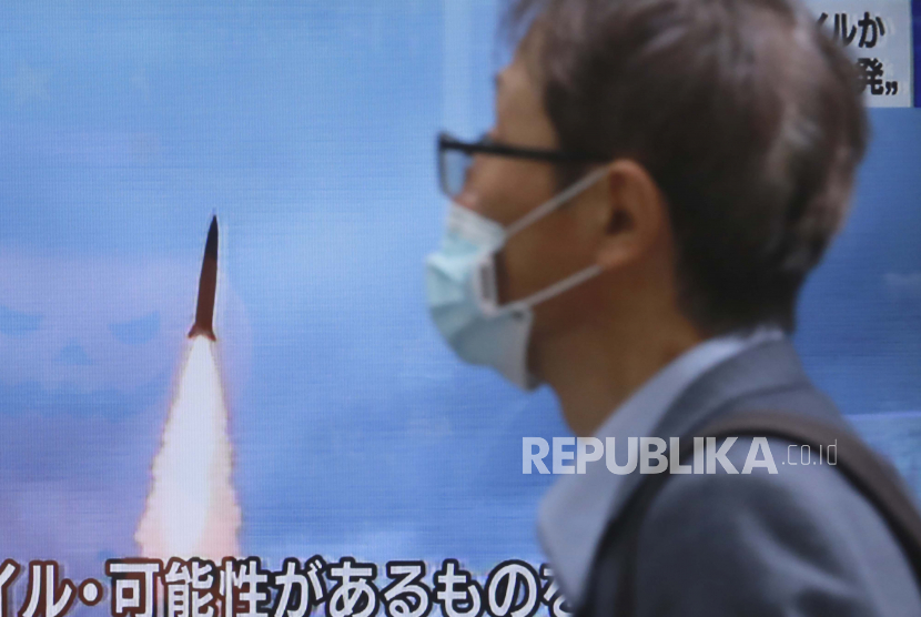  Seorang pria berjalan melewati layar TV yang menunjukkan program berita yang melaporkan tentang peluncuran rudal Korea Utara. Ilustrasi.